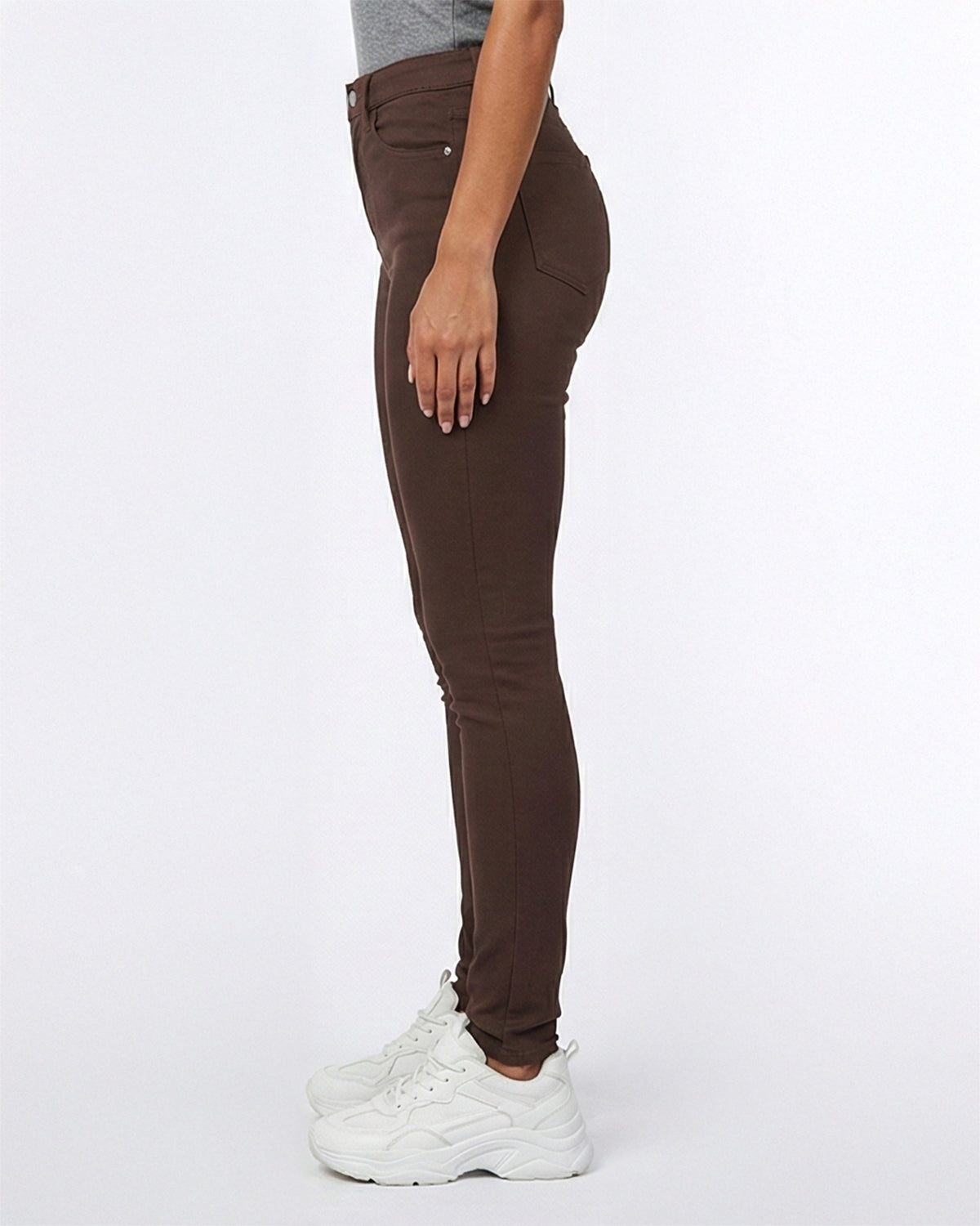 Side view of brown skinny jeans showing the fit on model