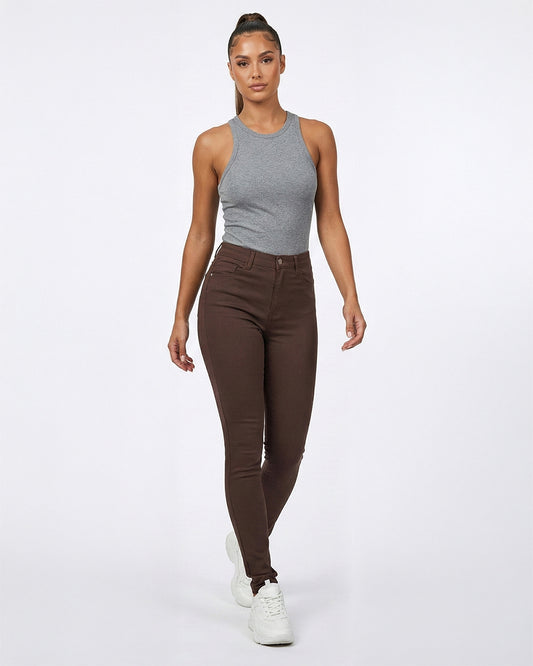 Woman wearing a gray tank top and brown skinny jeans on a white background