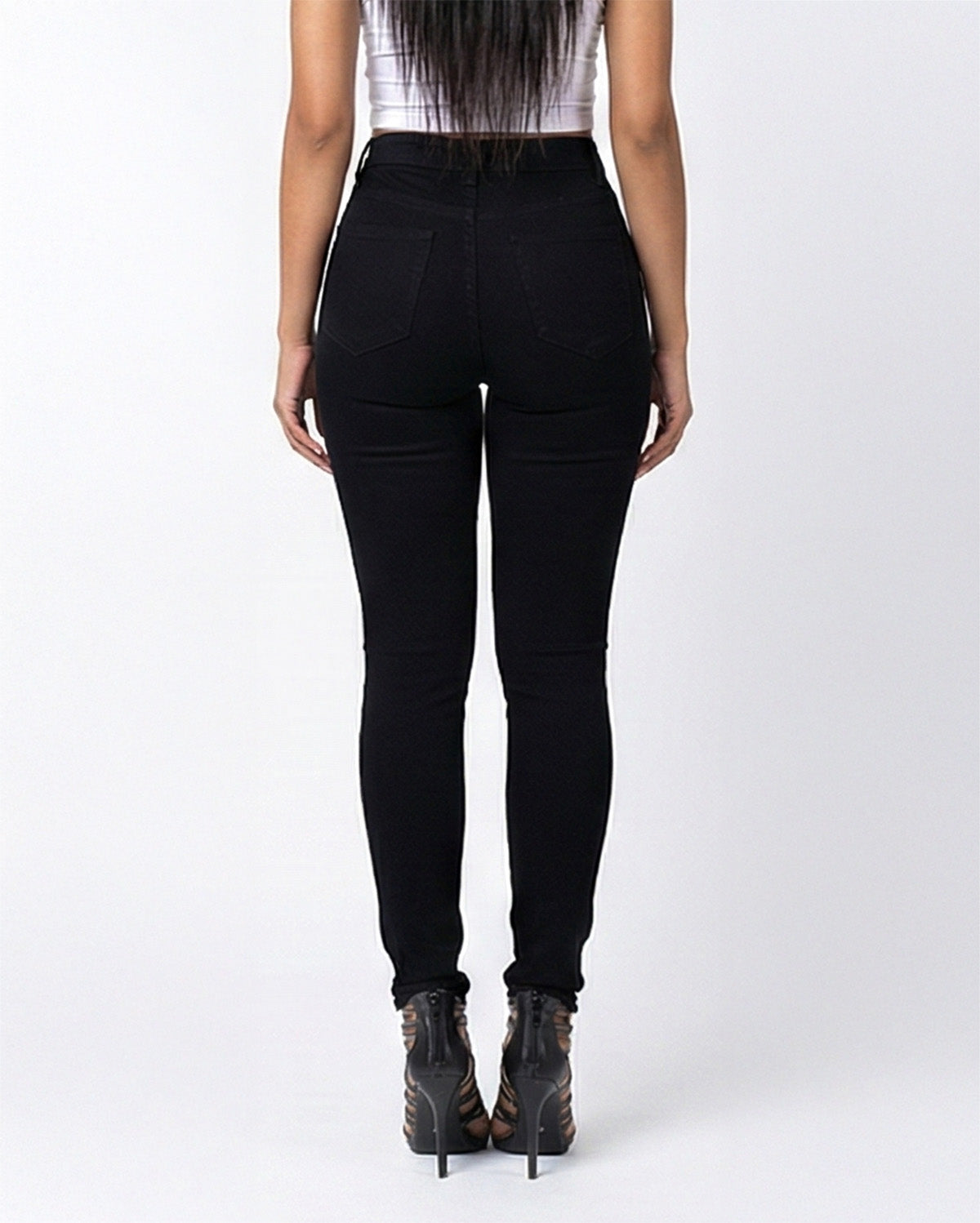 Back view of jet black stretch skinny jeans on a model