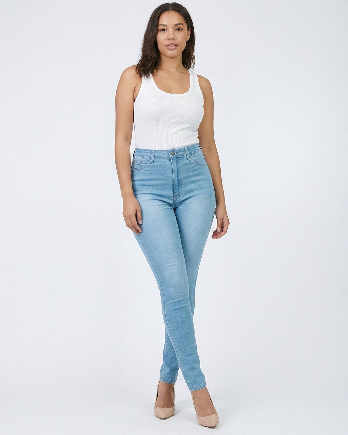 Woman wearing a light blue wash skinny jeans and a white tank top on a white background